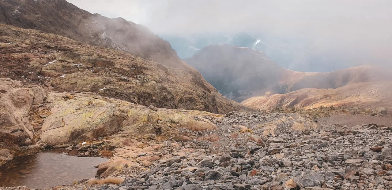 An impressive mountain landscape with colourful rocks, deep valleys and misty skies.