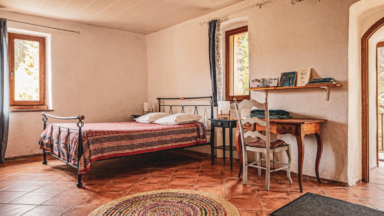Warm room with bed and desk, bathed in natural light, ideal for a getaway.