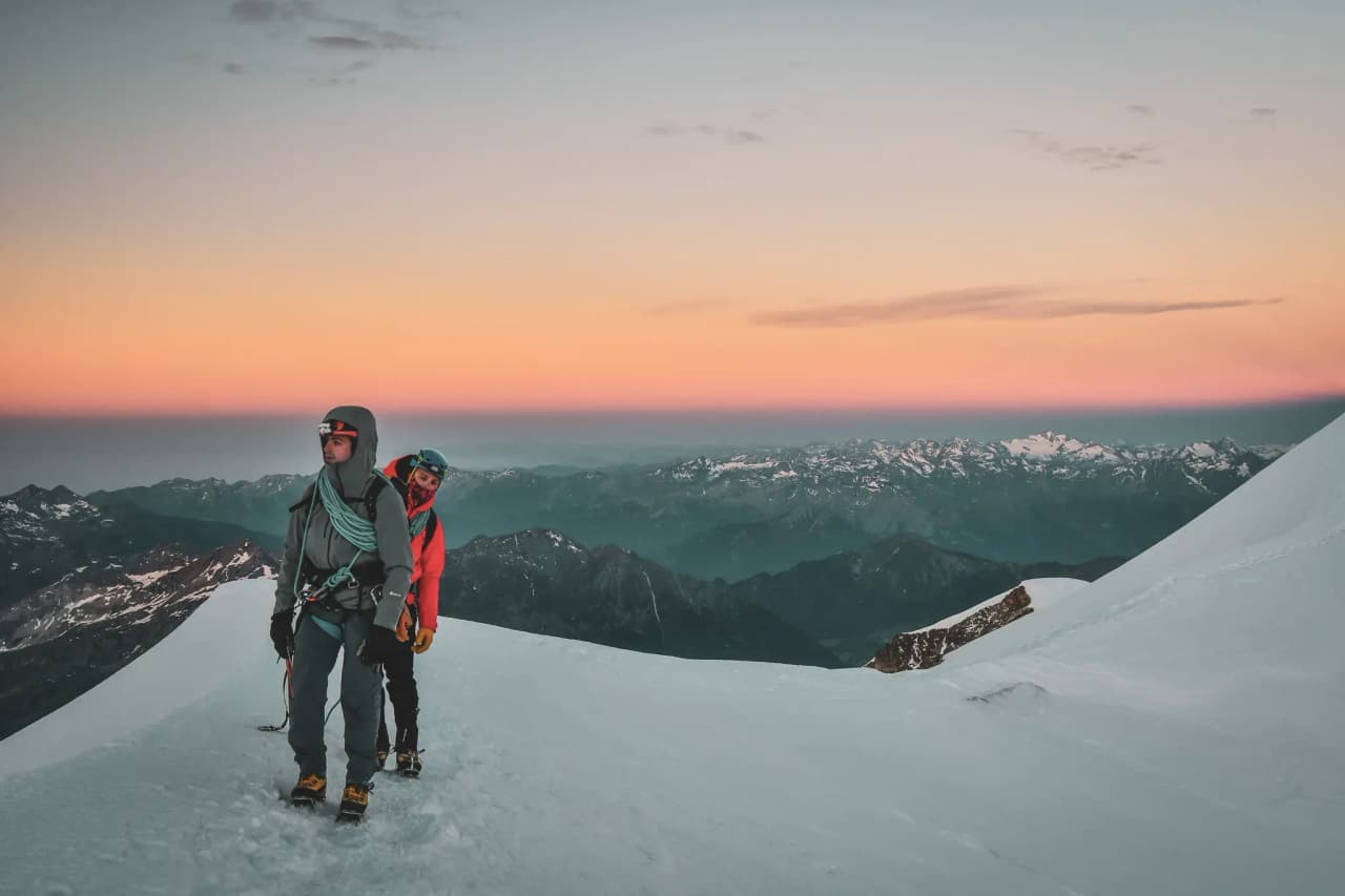 Adventurers on a glacier, admiring the sunrise over the majestic peaks.