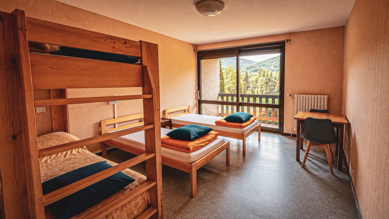 Bright room with wooden beds and views of the countryside, perfect for a mountain expedition.