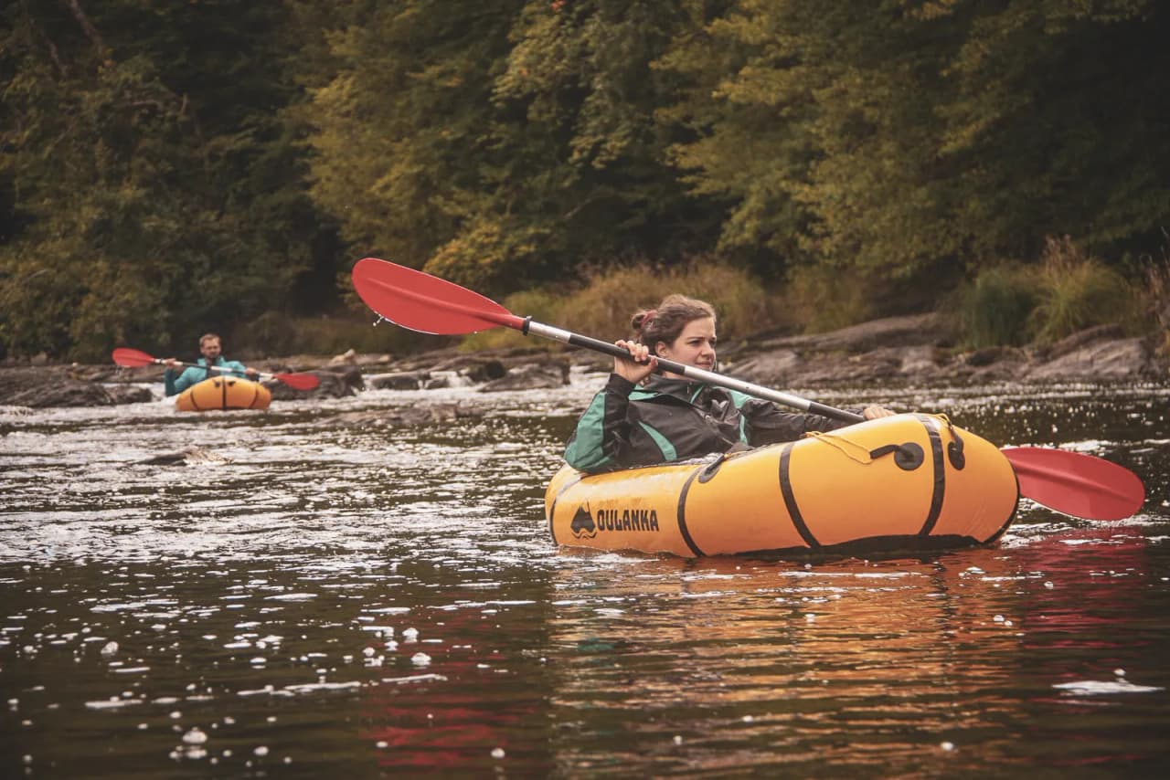 Two people were paddling peacefully in a packraft on the beautiful Semois, surrounded by greenery.