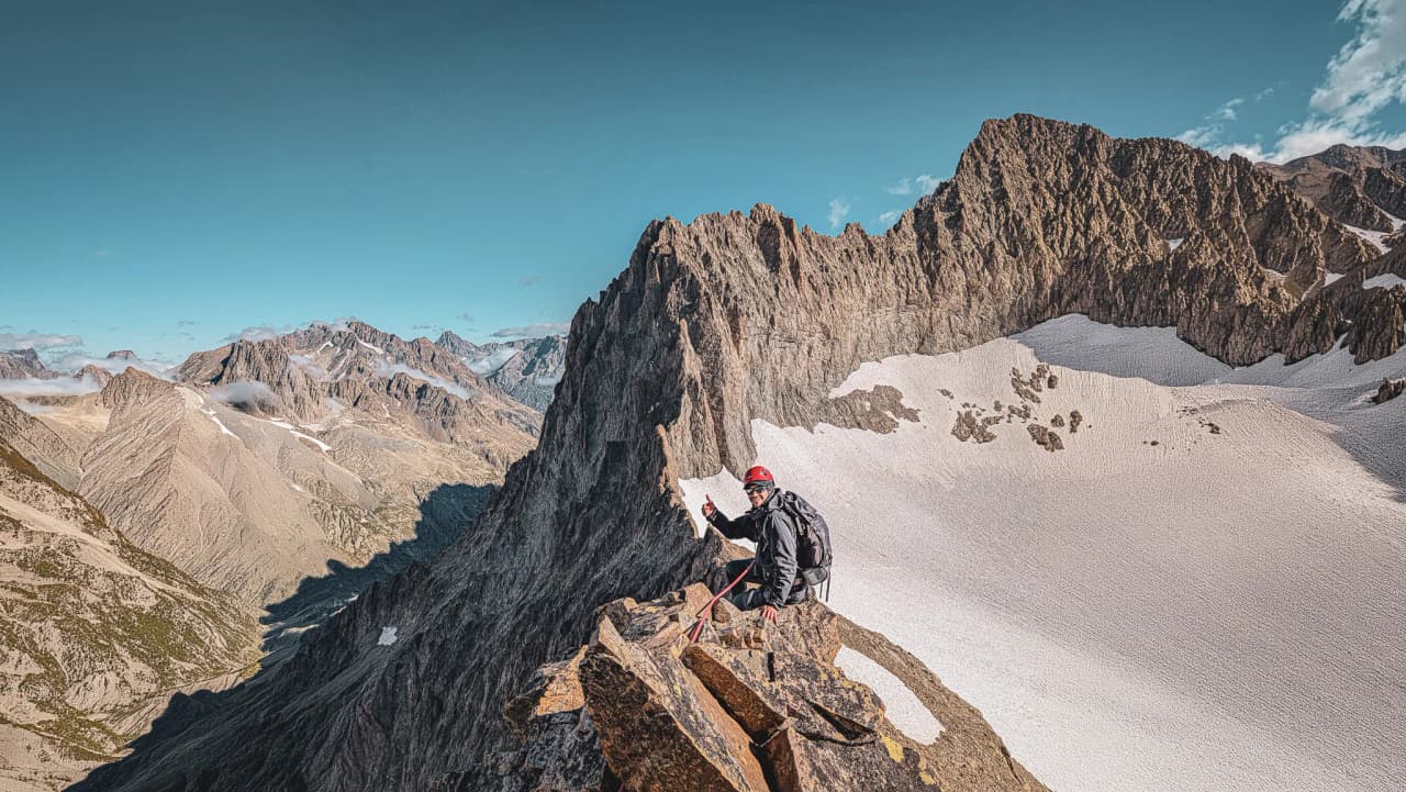 A mountaineer at the summit, surrounded by majestic mountains and dazzling glaciers, beckoning adventure.