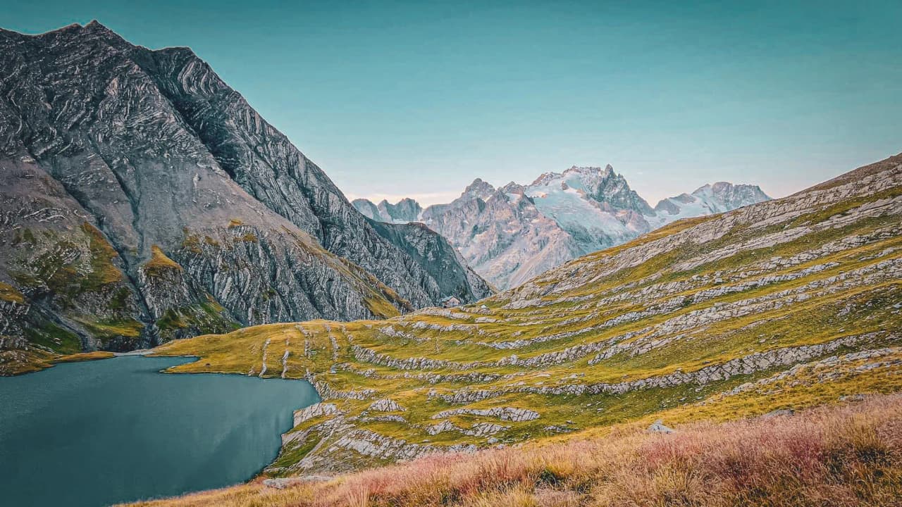 Majestic mountains, a turquoise lake and lush green meadows under a clear sky. Alpine escape.
