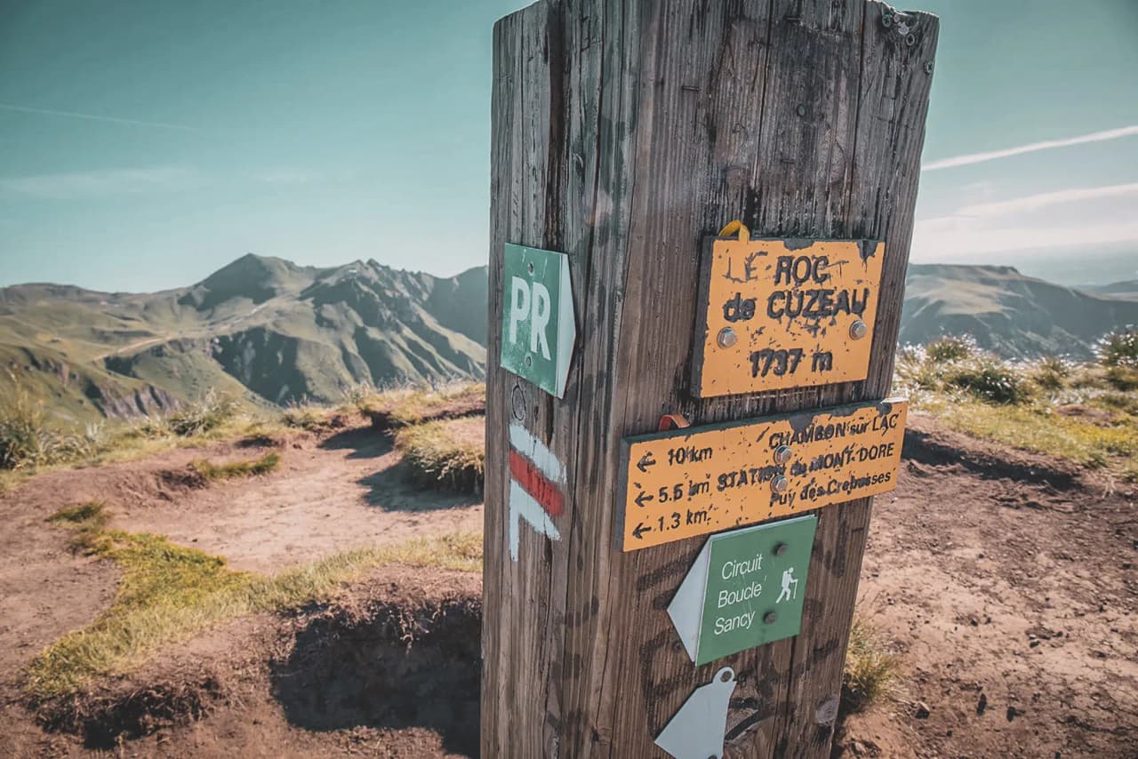Signpost at the top of the Roc de Cuzau, with majestic mountains in the background.