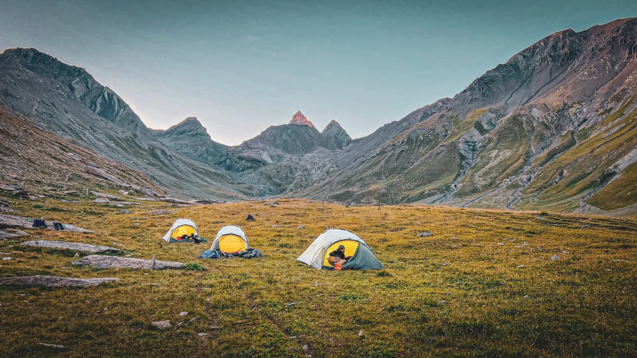 Camps under the Aiguilles d'Arves, with majestic mountains and the golden light of dusk.