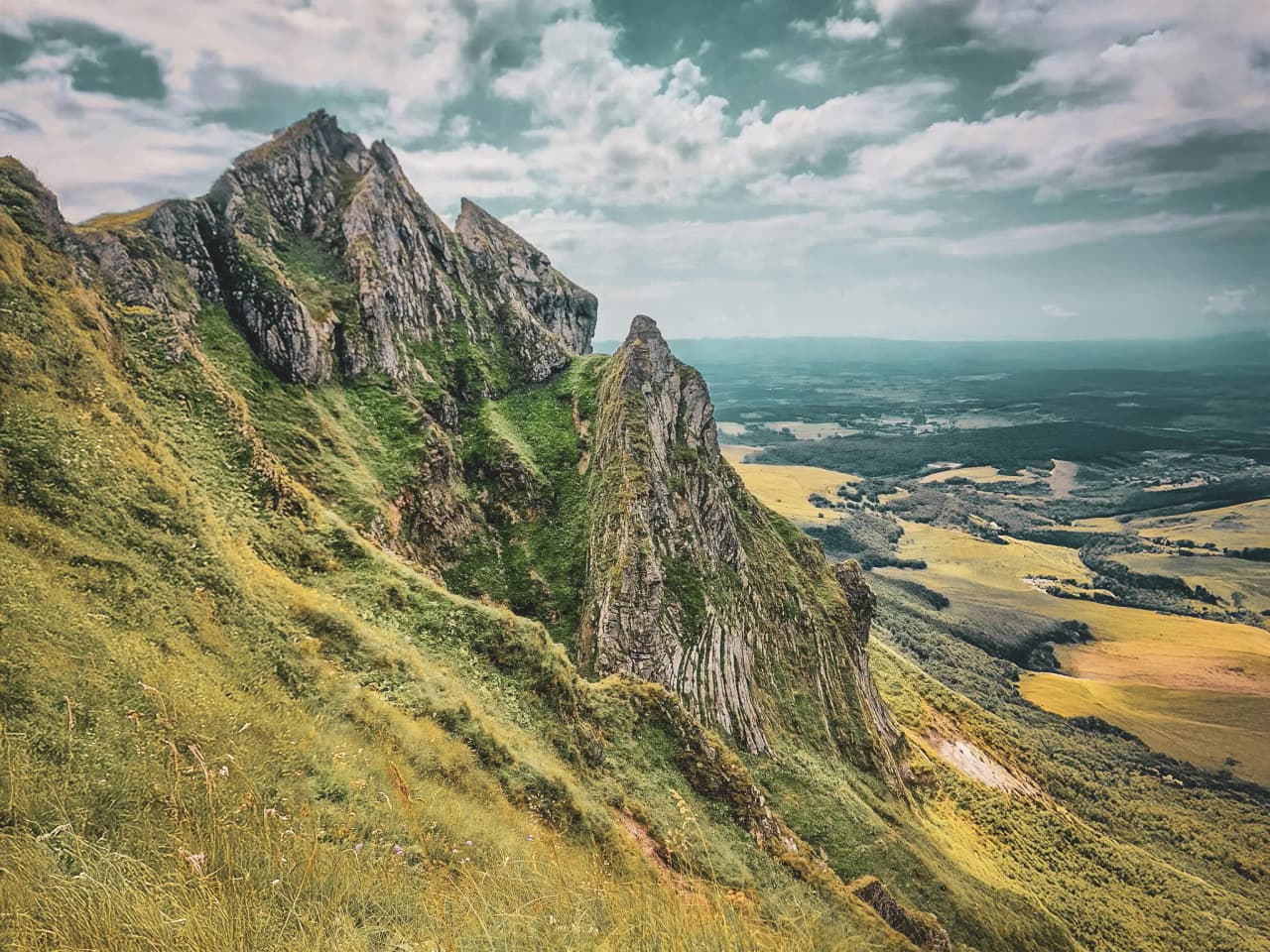 Majestic green volcanic ridges overlooking an idyllic Massif Central landscape.