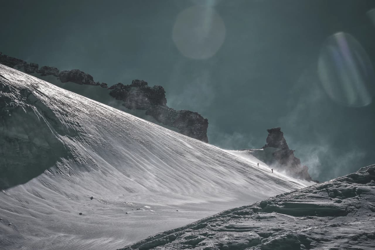 A majestic alpine scene with climbers on a snow-covered slope, ideal for adventure.