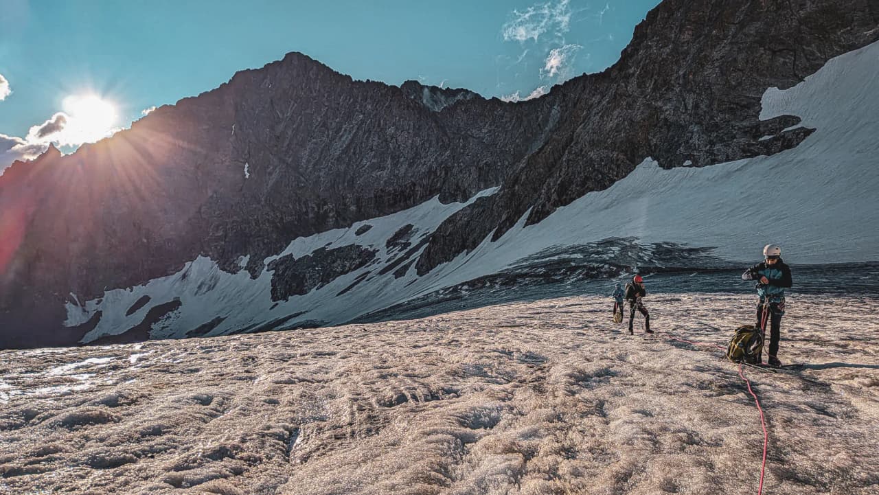 Mountaineers exploring a sun-drenched glacier in the Écrins, majestic peaks in the background.