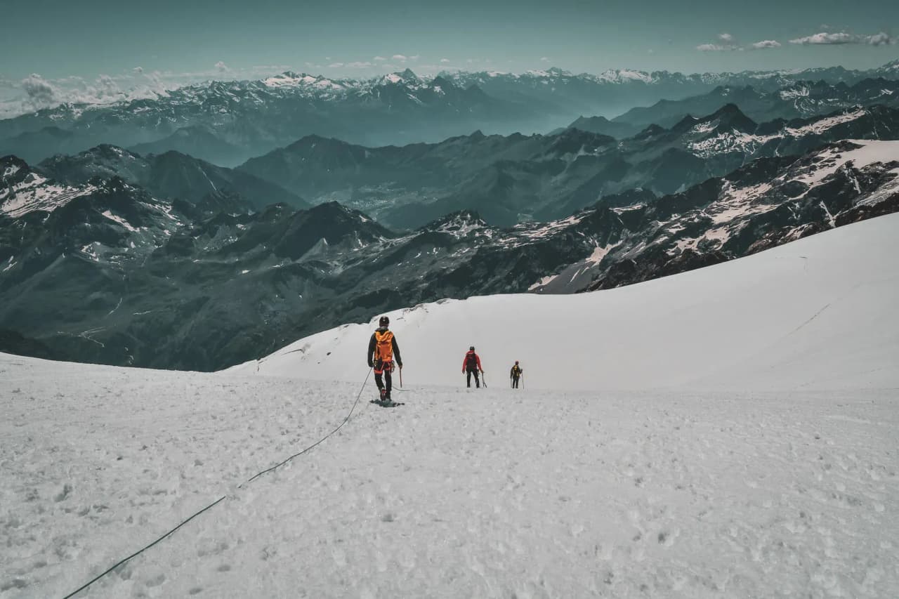 Mountaineers on a white glacier, with the majestic mountains in the background.