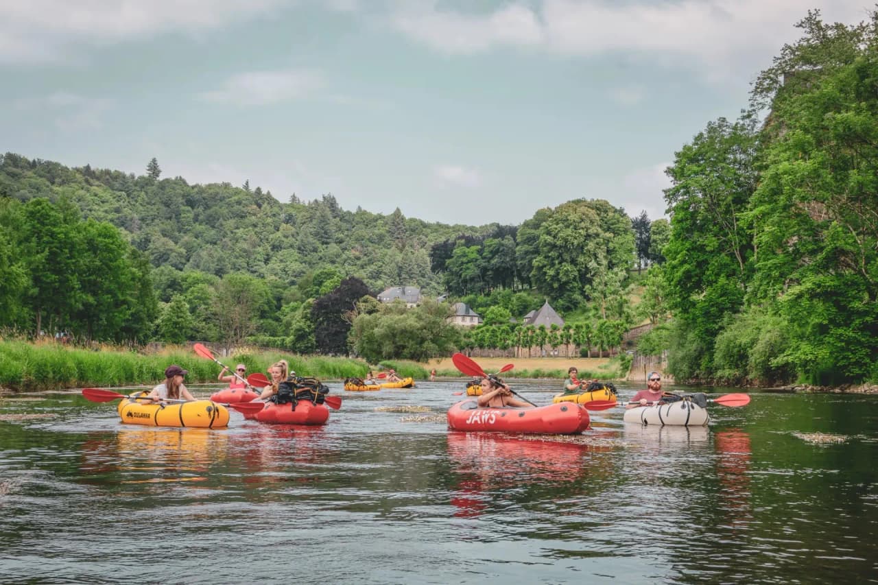 A group of packrafters cruising peacefully on the Semois, surrounded by lush green countryside.