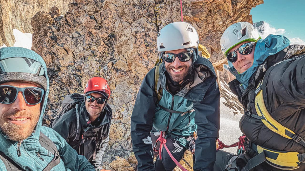 Four smiling climbers pose together on a rock face, ready for adventure.