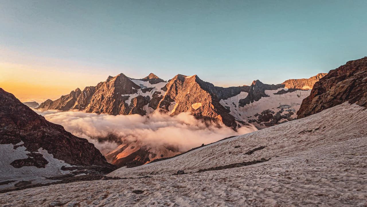 The majestic Écrins mountains bathed in light at sunrise, an enchanting spectacle.