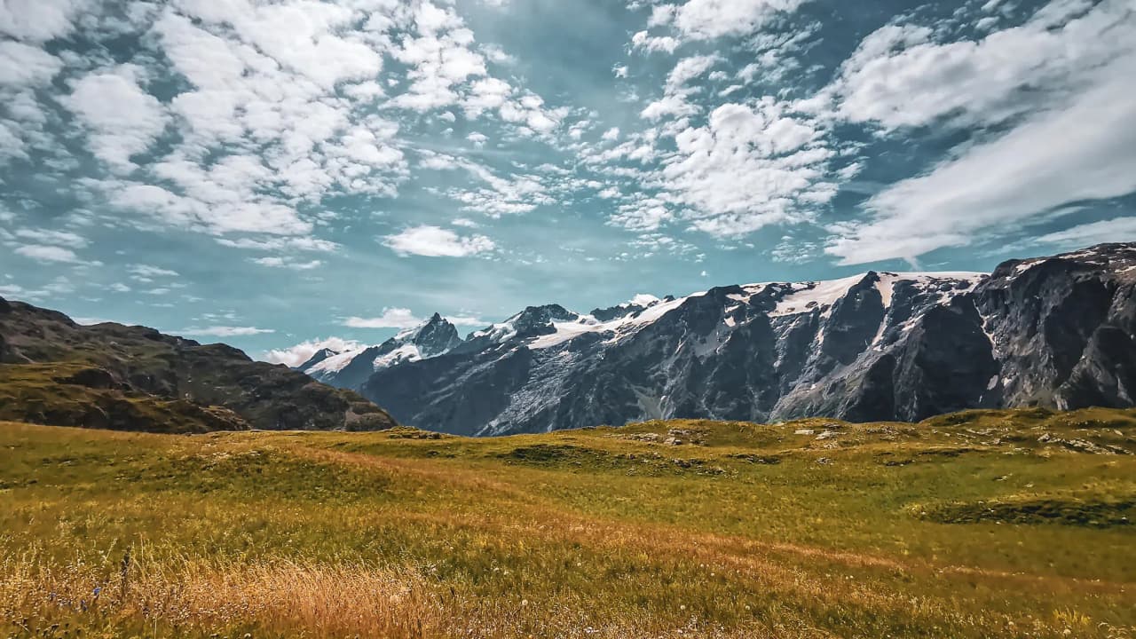Majestic panorama of the Emparis plateau, mountains and clouds in a luminous sky.