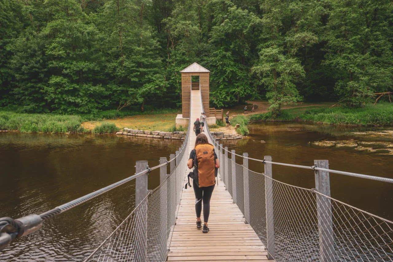 A suspension bridge over the Semois, surrounded by greenery, inviting you to enjoy an adventure in the heart of nature.