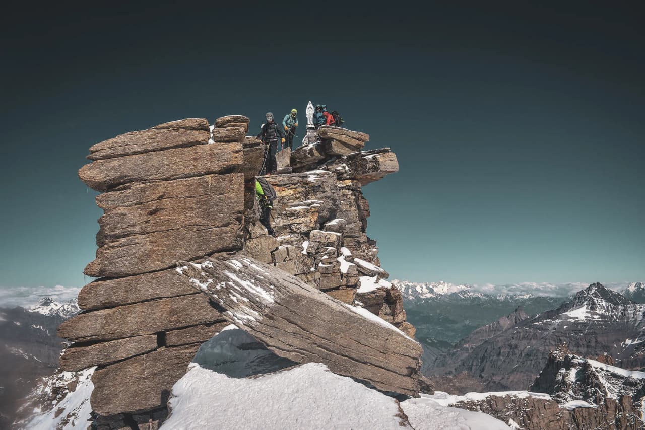 A group of climbers at the summit of Gran Paradiso, surrounded by breathtaking mountain scenery.