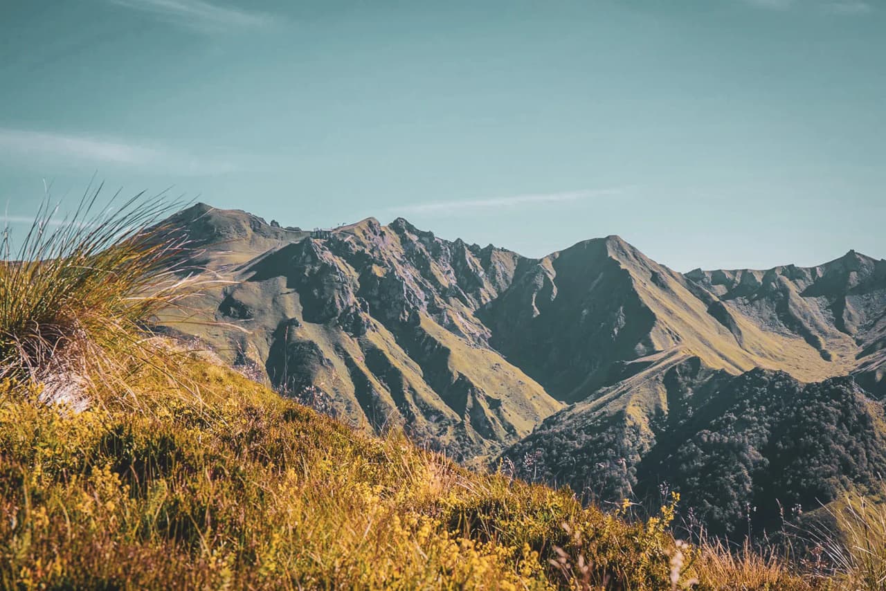 The enchanting landscape of the Massif Central, with green volcanic ridges under a clear blue sky.