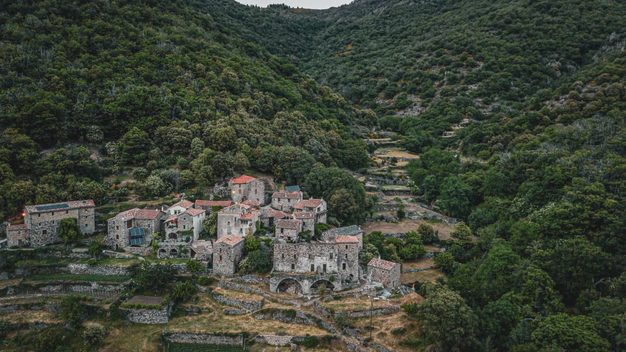 A picturesque village nestling in the Cévennes, surrounded by lush greenery and terraces.