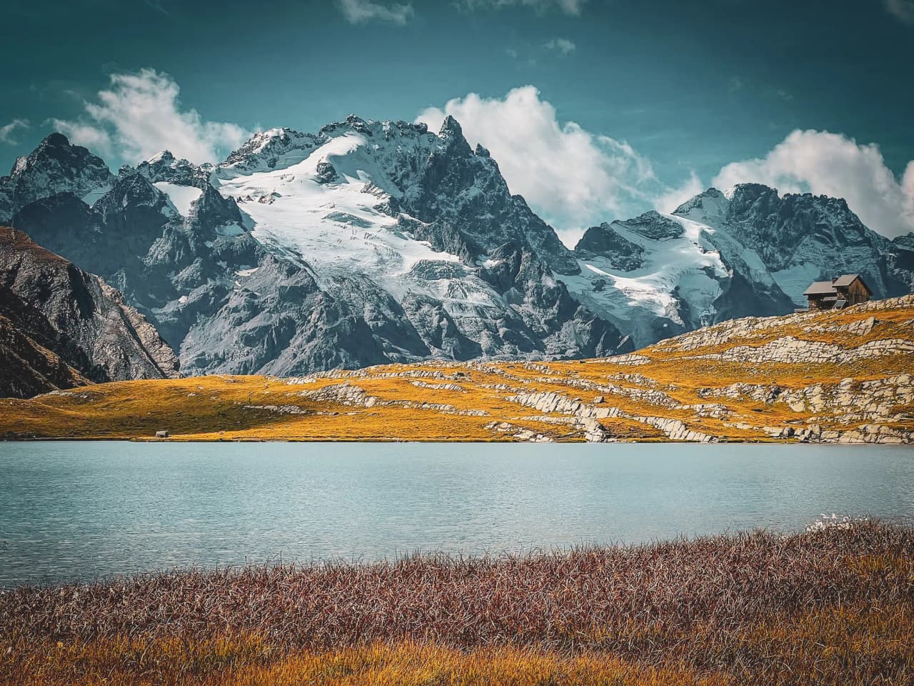 A turquoise lake surrounded by majestic mountains under a sunny sky, an invitation to escape to the Alps.
