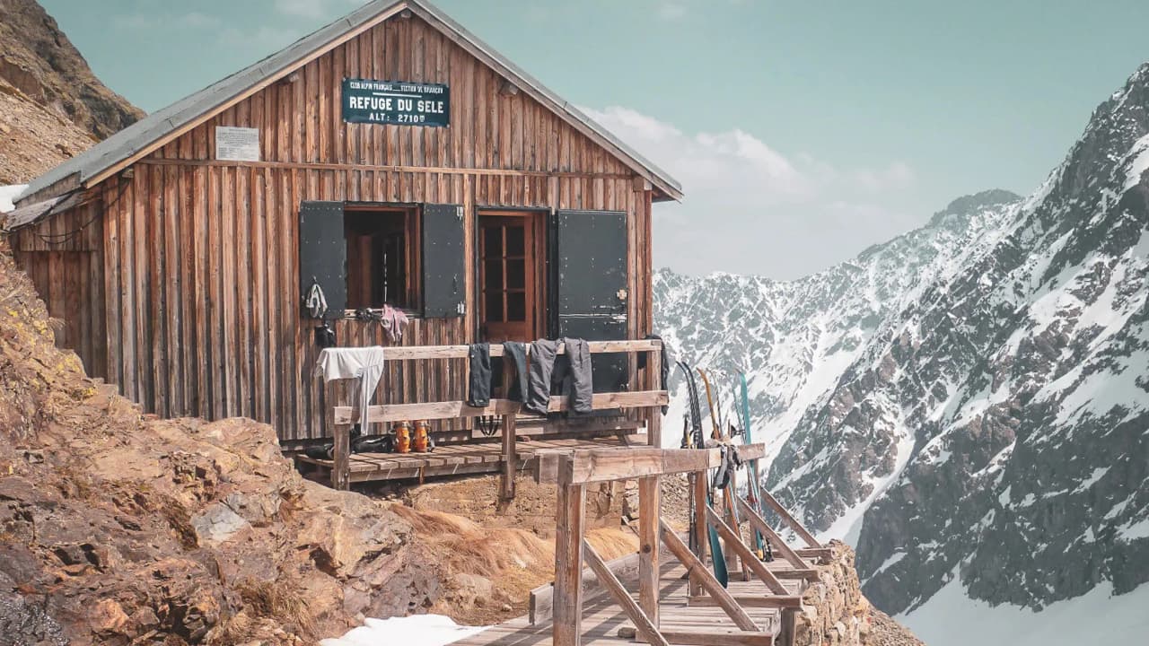 Wooden Mountain hut in the heart of the Écrins, with views of snow-capped mountains and blue skies. Escape guaranteed!