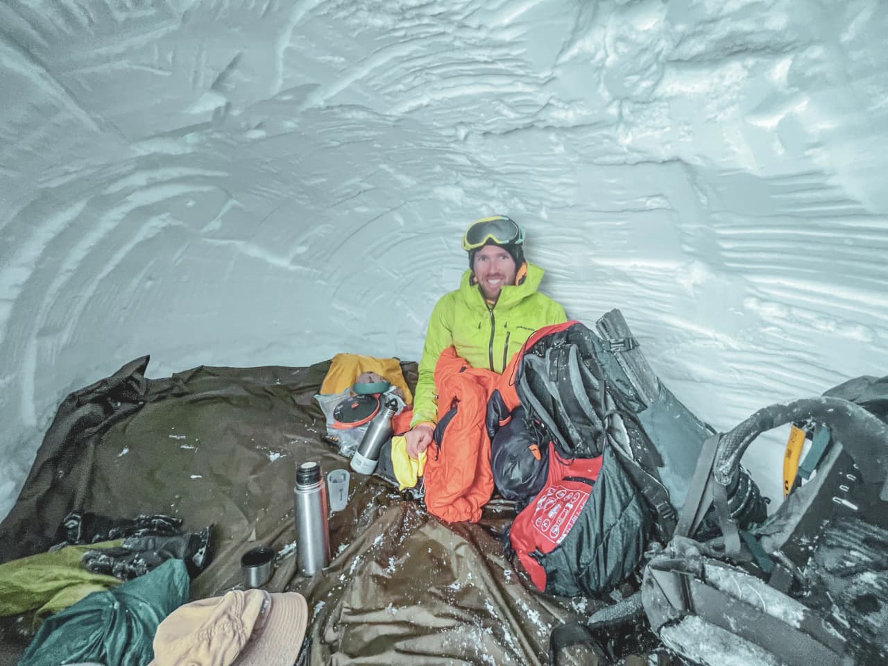 A smiling adventurer in an igloo, ready for a magical night facing the Meije.