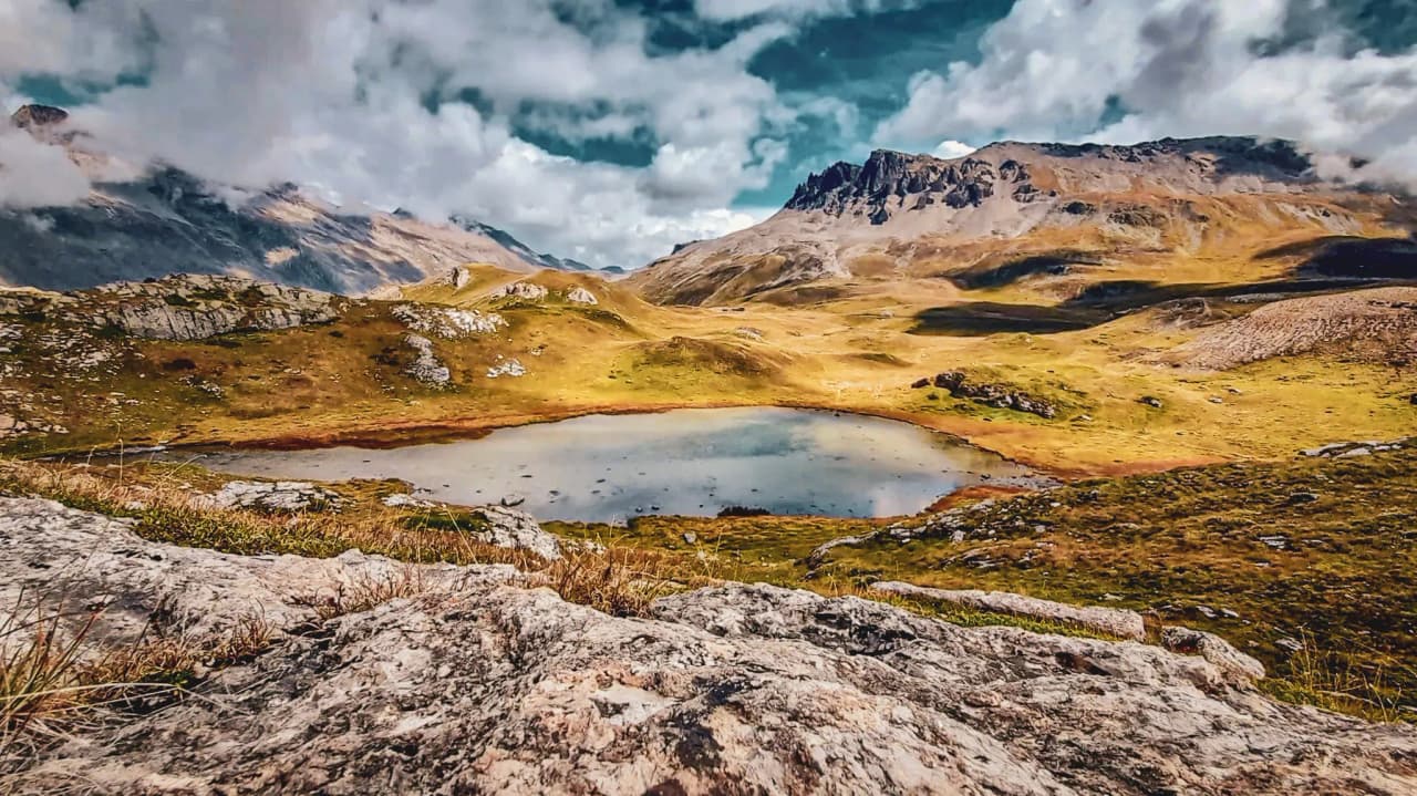 Lac paisible entouré de montagnes majestueuses, paysage sauvage invitant à l’évasion.