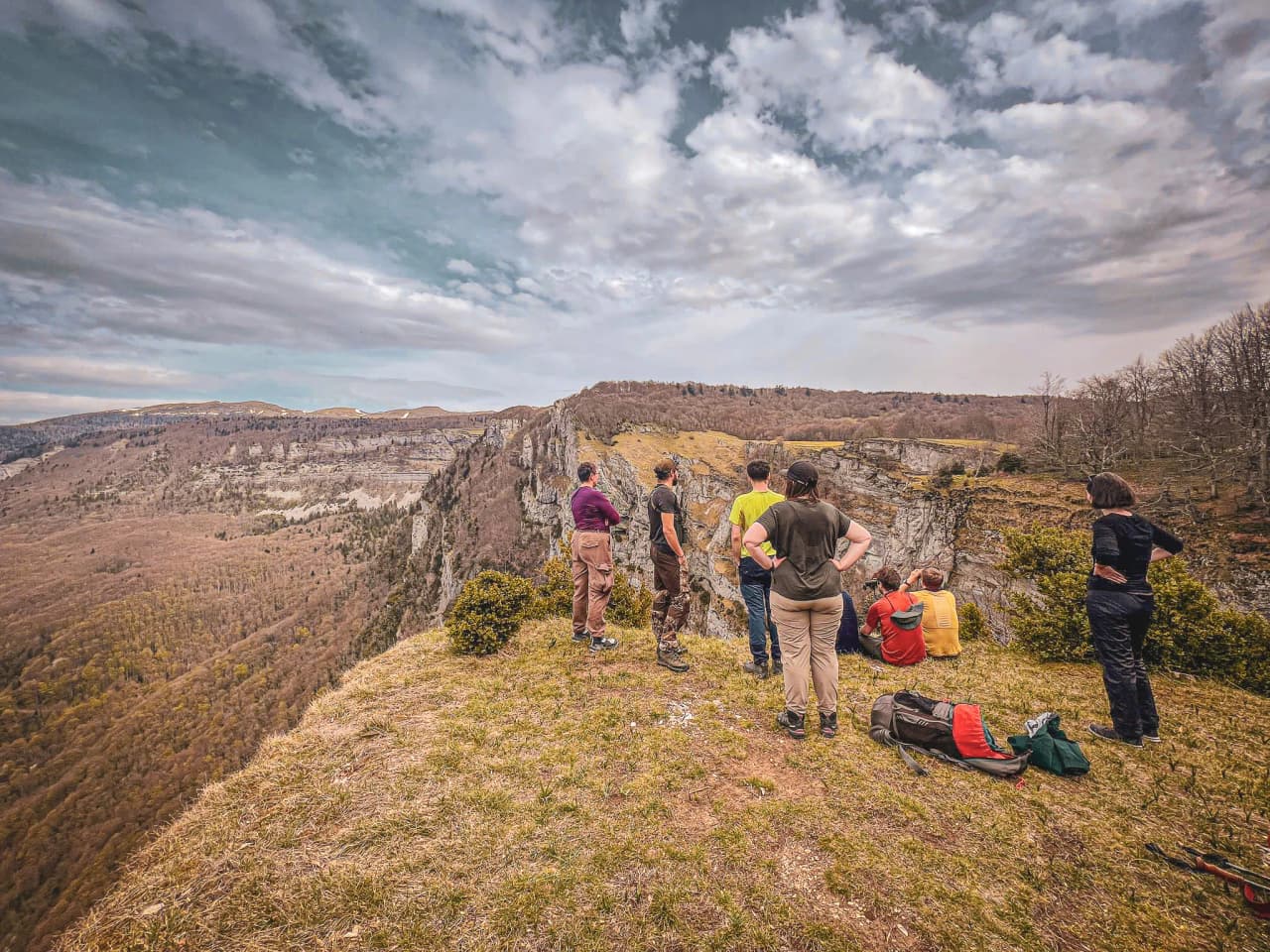 Groupe de randonneurs contemplant un panorama de falaises et de vallée, une scène immersive d’exploration outdoor et de paysages naturels spectaculaires.