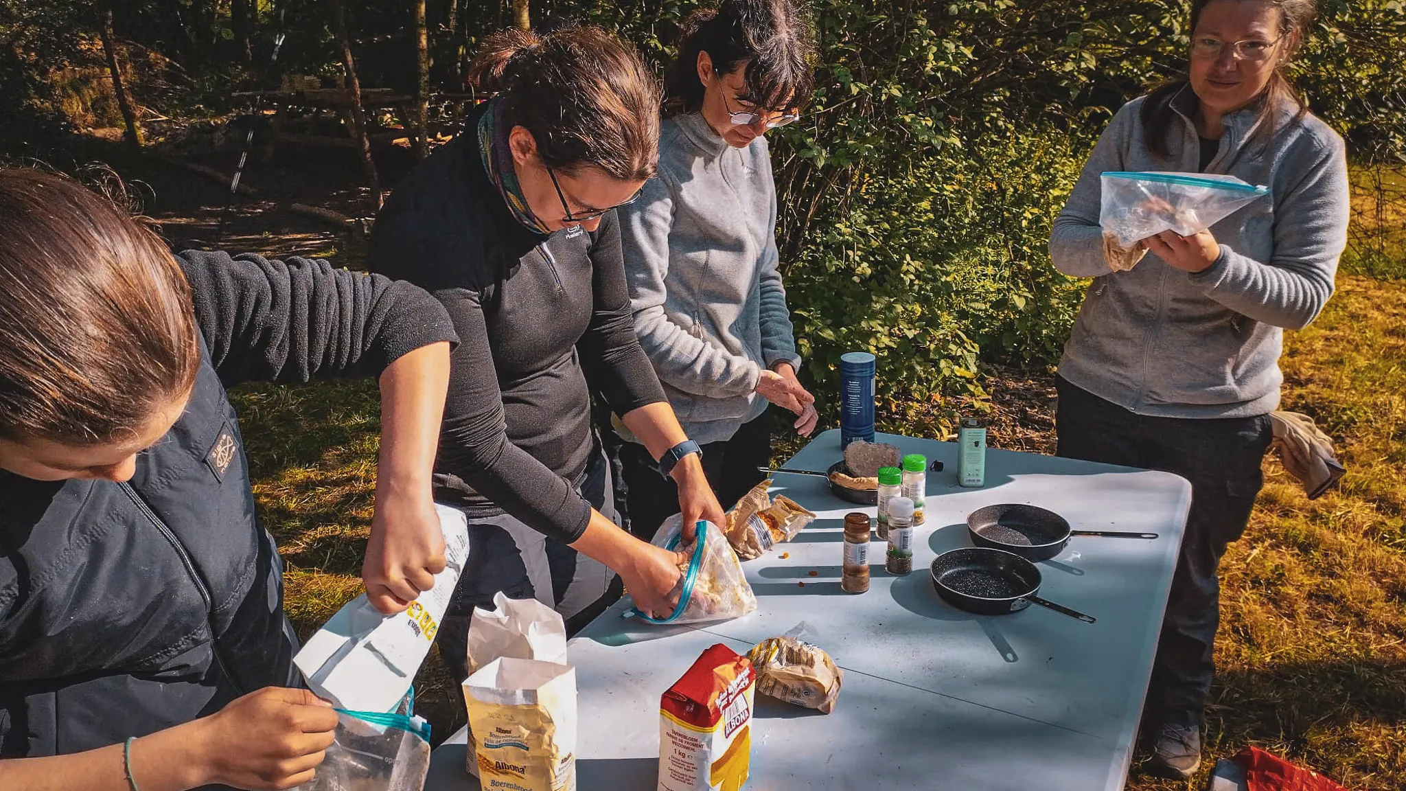Groupe en pleine préparation de repas en pleine nature, entouré de verdure et de bonne humeur.