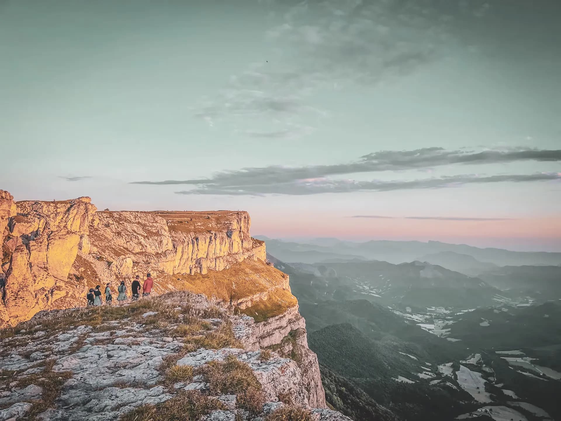 Groupe de randonneurs sur un sommet du Vercors, face à un paysage spectaculaire au coucher de soleil.
