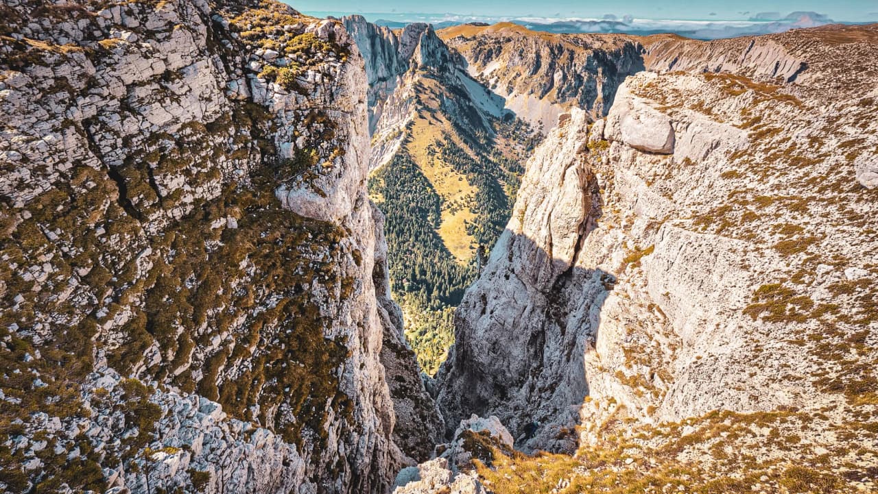 A majestic panorama of Mont Aiguille, rocky walls and a green, sun-drenched valley.