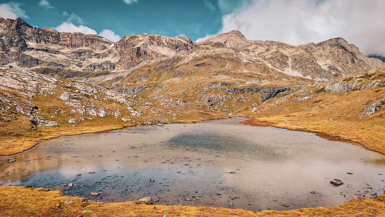 Lac paisible entouré de montagnes escarpées, reflet du ciel bleu, invitation à l'aventure.
