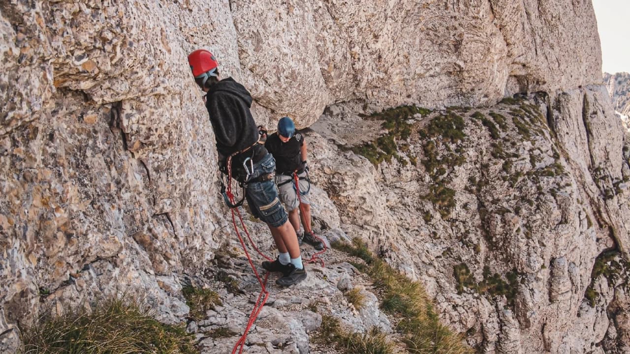 A silhouetted climber against a vibrant sky, majestically ascending Mont Aiguille.
