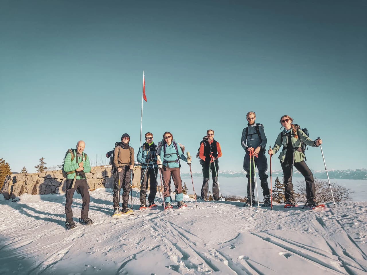 Group of hikers on snowshoes, admiring an Alpine panorama.