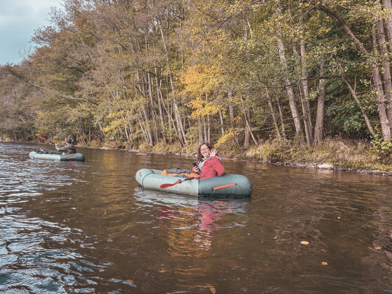 Un groupe en packraft sur une rivière entourée de belles forêts dorées en Ardenne.