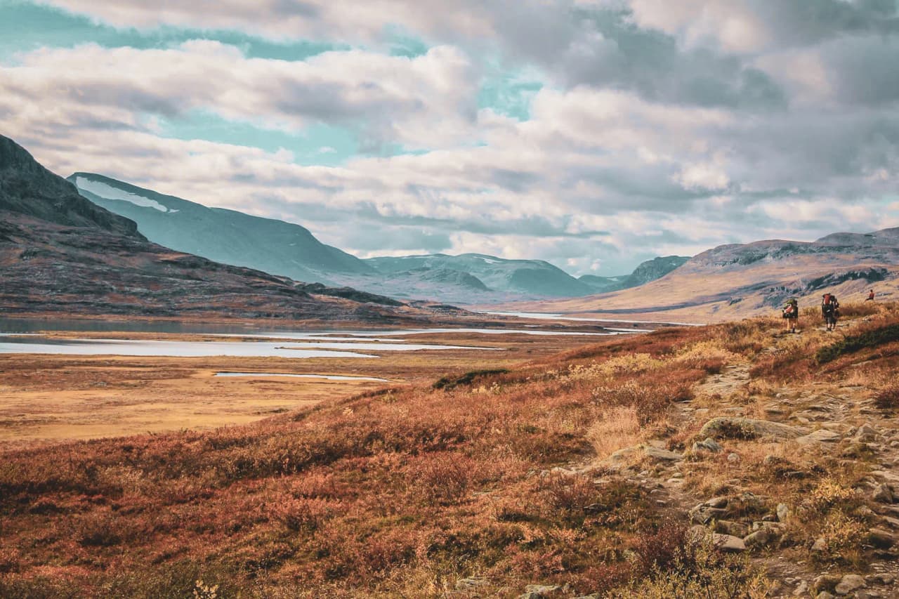Des randonneurs explorent des paysages époustouflants en Laponie, entre montagnes et lacs.