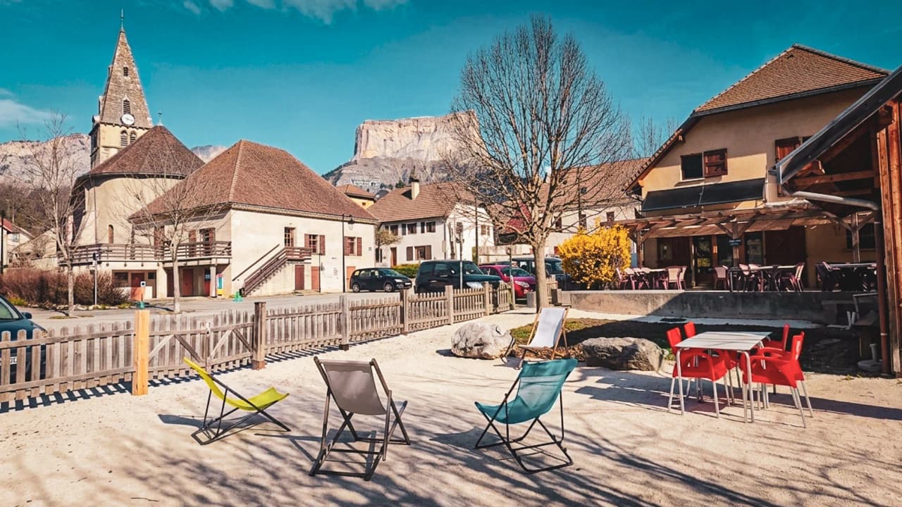 A charming village square with colourful chairs, majestic mountains and blue skies.