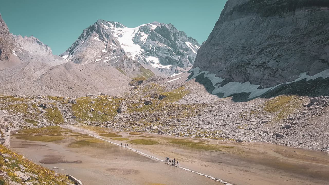 A group of hikers traverse spectacular Alpine scenery, surrounded by majestic mountains.