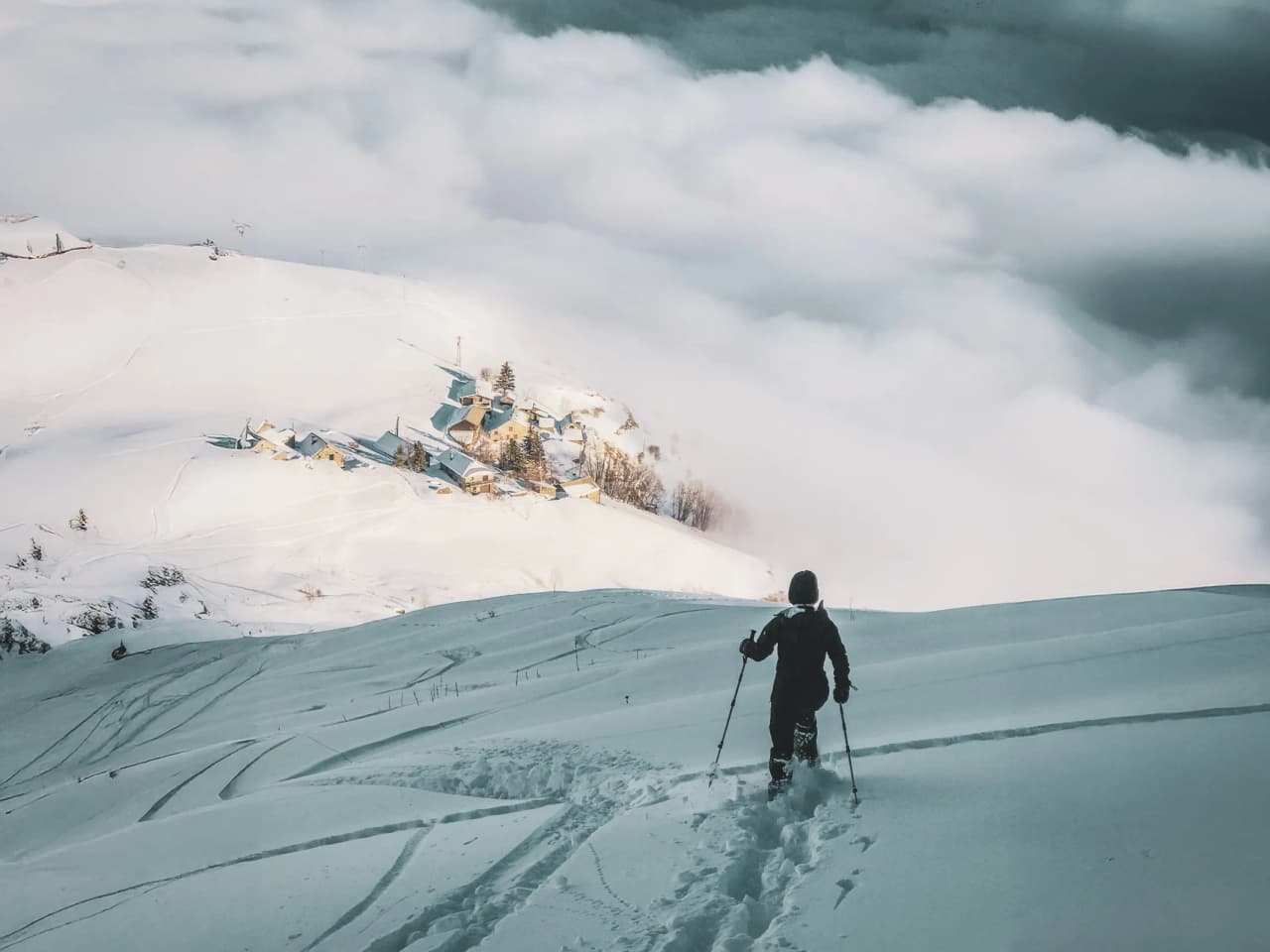 Snowshoe trekking on immaculate snow, with a view of a village in the clouds.