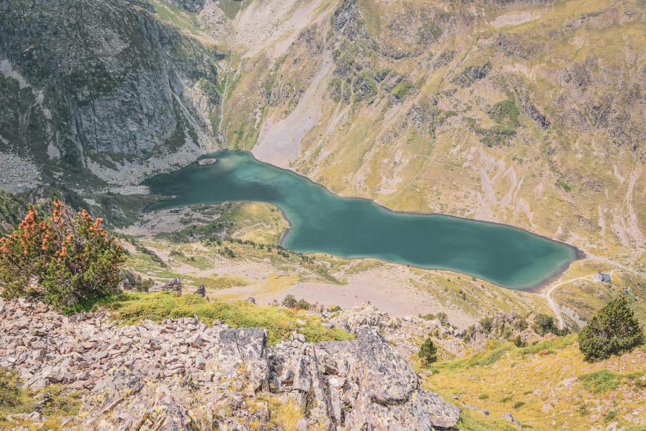 Un lac turquoise entouré de montagnes verdoyantes et de rochers, invitation à l'aventure.