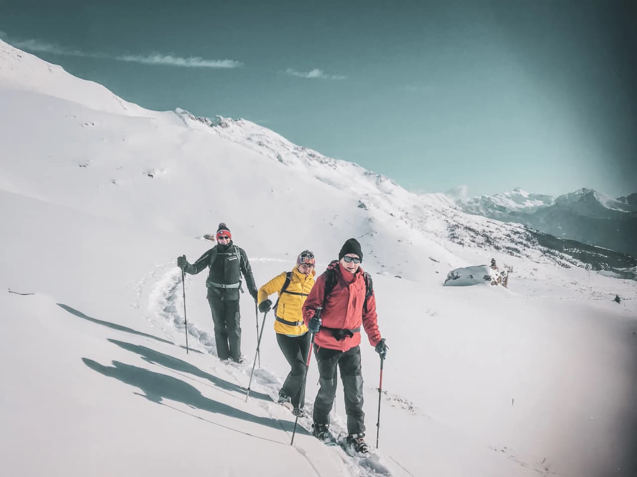 Snowshoe hikers heading for majestic panoramas of the Écrins, under clear skies.