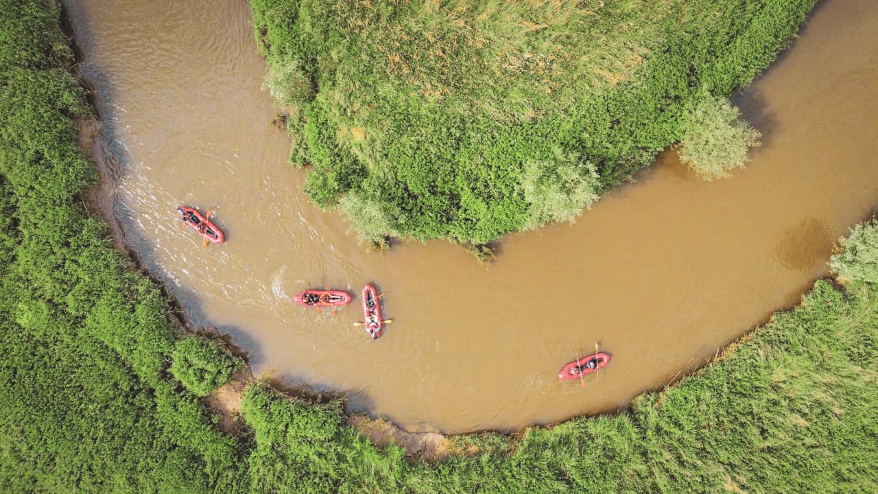 Packraft sur une rivière sinueuse entourée de verdure luxuriante en Belgique.