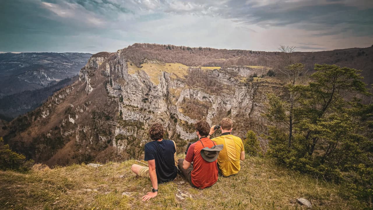 Trois aventuriers contemplent un paysage montagneux majestueux dans le Vercors.