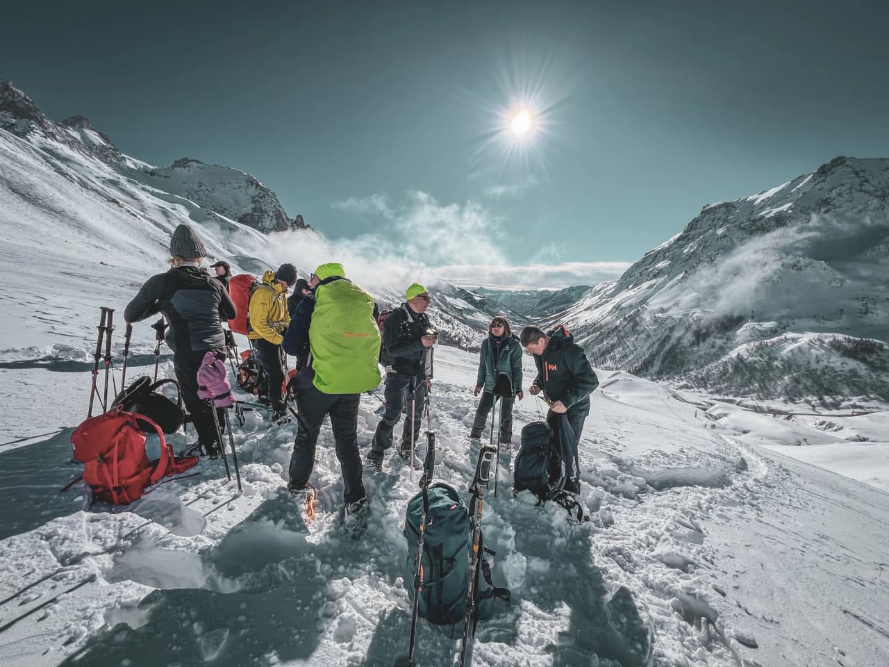 A group of snowshoe hikers in the sunshine, facing the majestic glaciers of the Écrins.