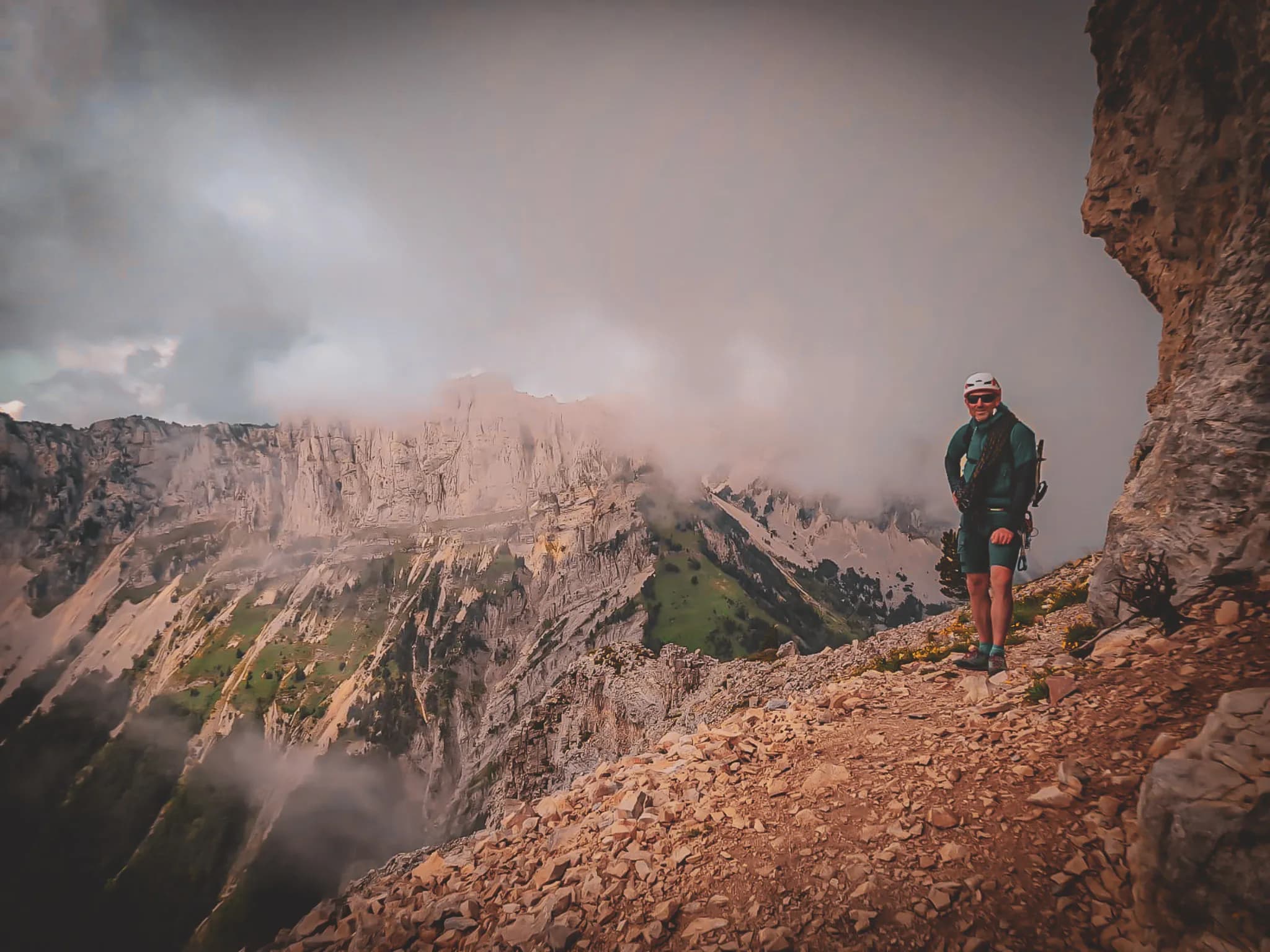A smiling climber on a steep path, surrounded by the spectacular scenery of the Vercors.