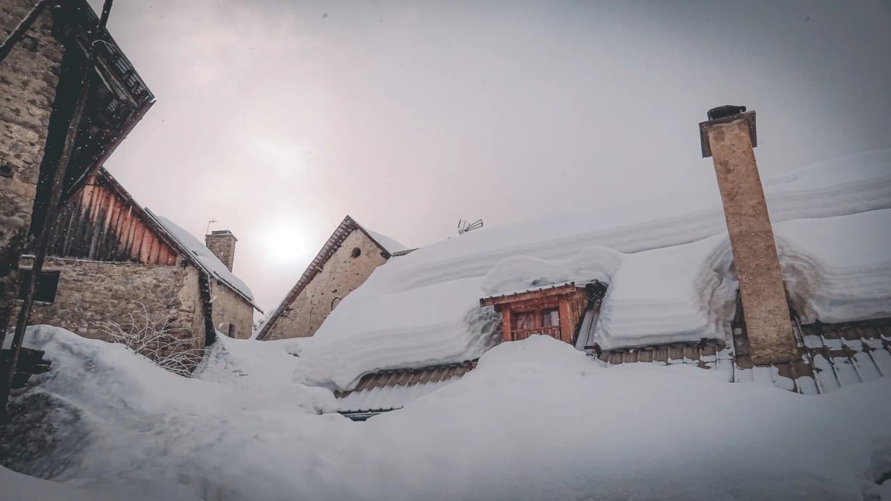 A view of an enchanting alpine setting, houses buried under the snow, a magical winter atmosphere.