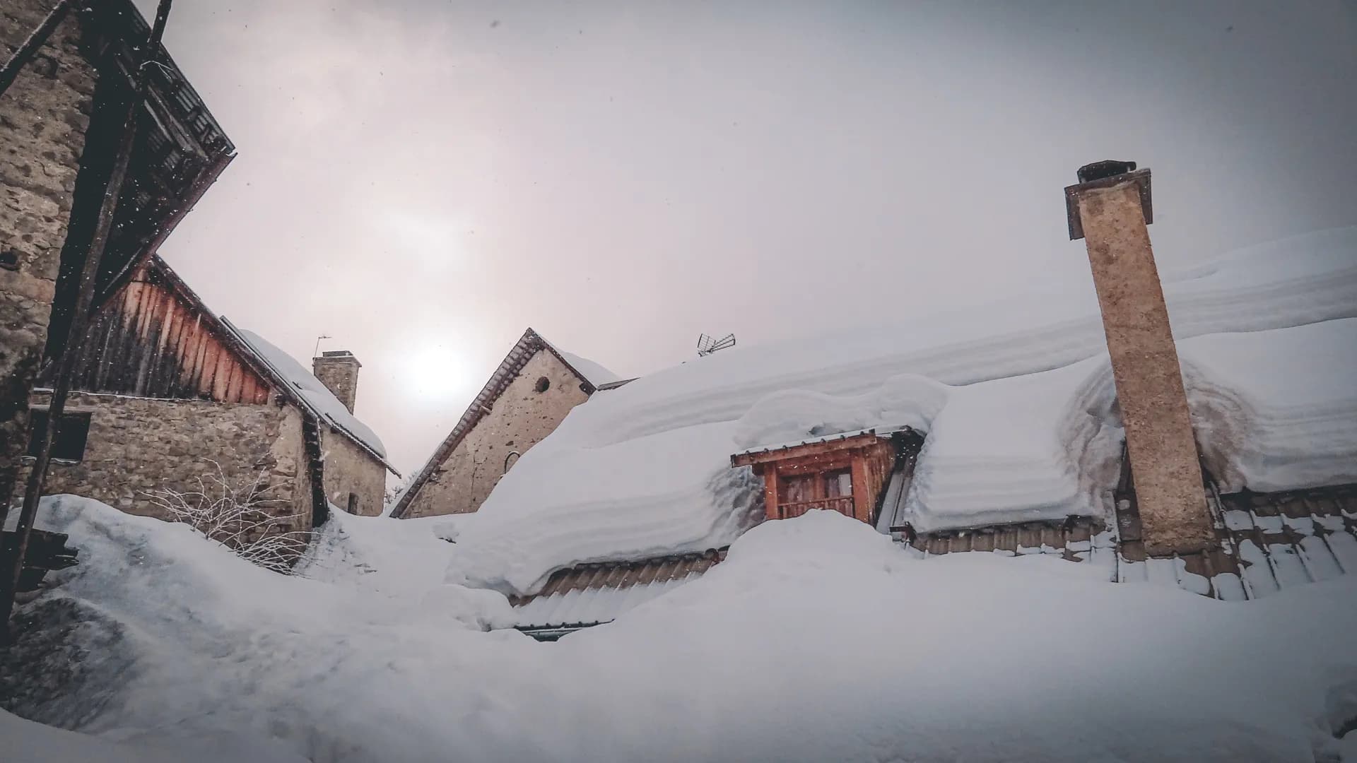 A view of an enchanting alpine setting, houses buried under the snow, a magical winter atmosphere.