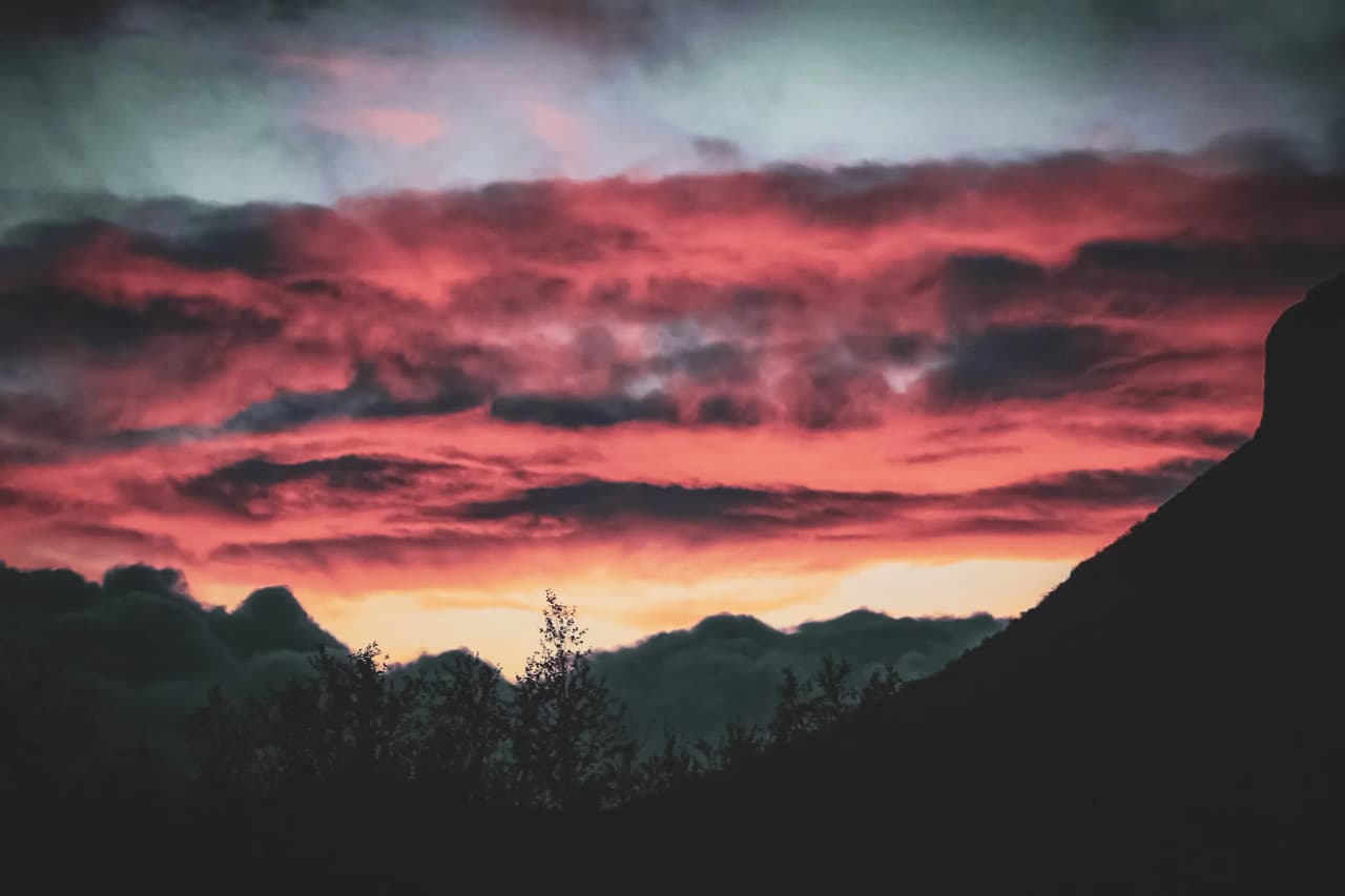 Coucher de soleil flamboyant sur les montagnes et nuages en Laponie, invitant à l'aventure.
