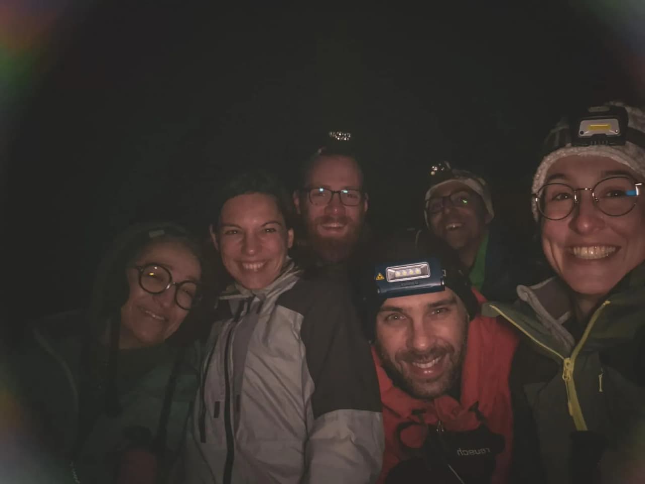 A smiling group in the middle of the night, ready for a snowshoeing adventure in the Swiss Jura.