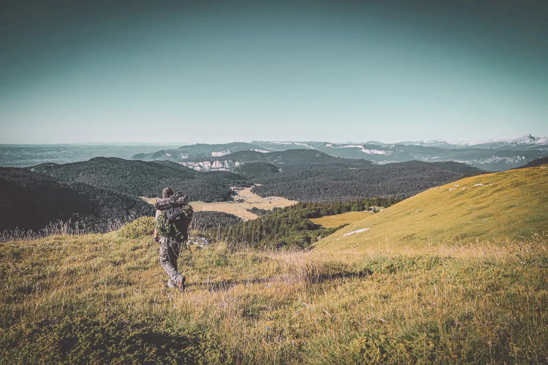 Randonneur explorant les paysages montagneux du Vercors, entre prairies verdoyantes et sommets.