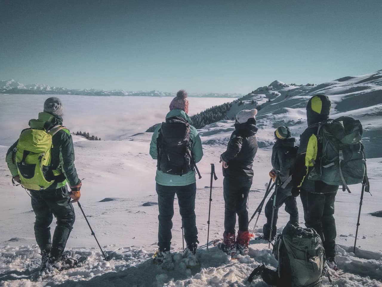Five hikers admire a snowy panorama, ready for a winter adventure in the Jura.