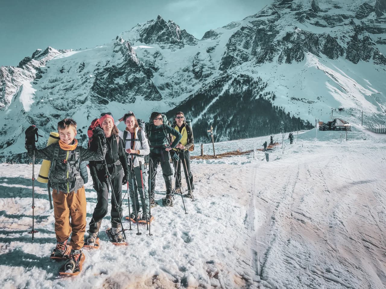 A happy group on snowshoes in a snow-covered Alpine landscape, ready for adventure.